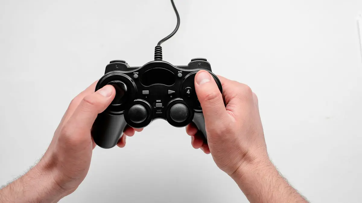 Two hands holding a black wired game controller against a plain white background