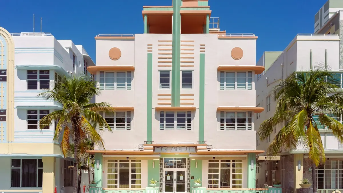 Pastel Art Deco hotel with palm trees in Miami Beach under a blue sky